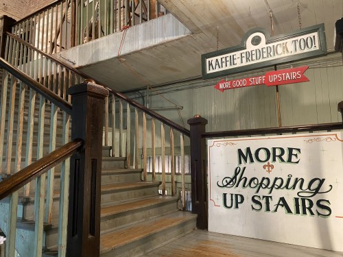 Staircase leading to an upper level with signs for "Kaffie-Frederick, Too!" and "More Shopping Up Stairs."
