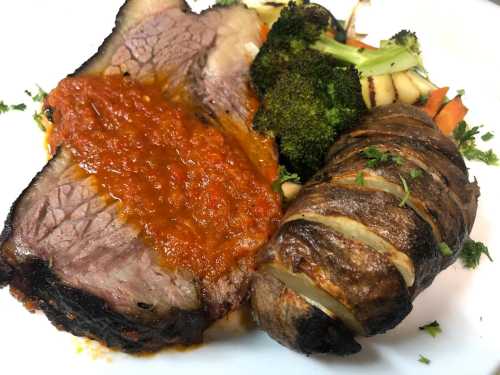 A plate featuring sliced roast beef with sauce, a stuffed meat roll, and steamed broccoli and carrots.