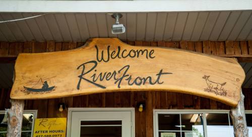 Wooden sign reading "Welcome RiverFront" with a canoe and a fox illustration.