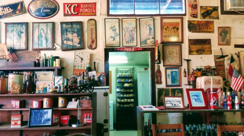 A vintage interior filled with old signs, memorabilia, and shelves of products, creating a nostalgic atmosphere.