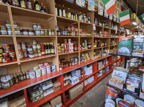 A well-stocked grocery store aisle with shelves of jars, bottles, and boxes of various food products.