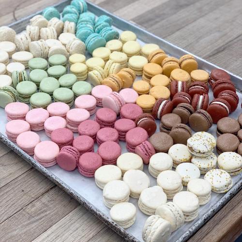 A tray filled with colorful macarons in various flavors and pastel shades, arranged neatly.