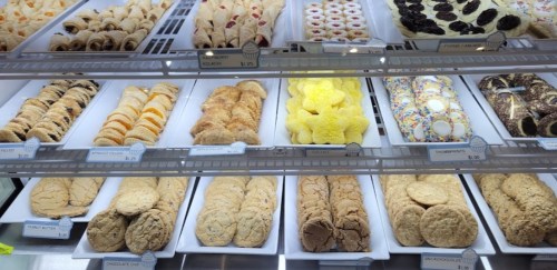 A display case filled with various cookies and pastries, including colorful sprinkles and cream-filled treats.