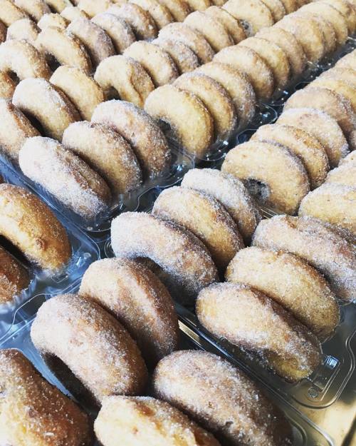 A close-up of rows of sugar-coated donuts arranged neatly in a tray.
