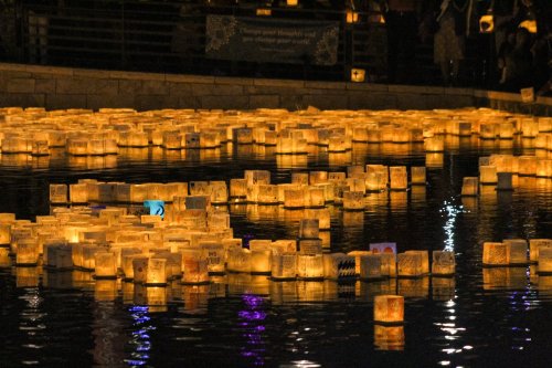 Floating lanterns illuminate a serene water surface at night, creating a tranquil and magical atmosphere.