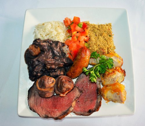 A plate featuring rice, diced tomatoes, seasoned meat, and various side dishes, arranged artfully.