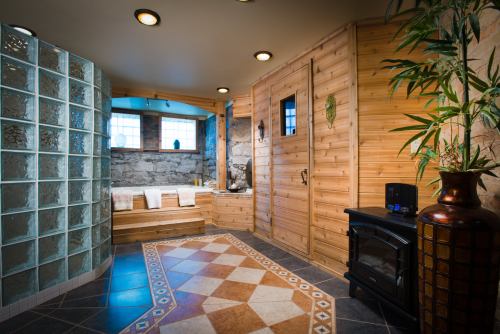 A cozy spa-like room featuring wooden walls, a glass block shower, and a decorative tiled floor.