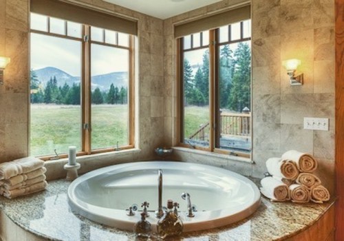 Luxurious bathroom with a round tub, large windows, and a scenic view of mountains and greenery. Soft towels are neatly arranged.