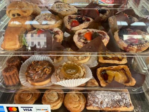 A display case filled with various pastries, including fruit tarts, danishes, and cinnamon rolls.