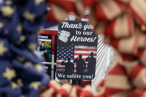 A sign thanking heroes, featuring silhouettes saluting against an American flag backdrop, framed by red, white, and blue decor.