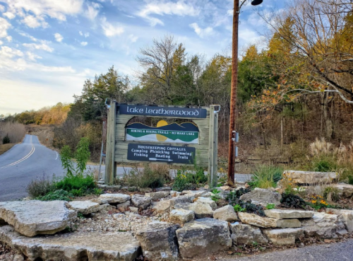 Sign for Lake Leatherwood with information on cottages, camping, fishing, and trails, surrounded by natural scenery.