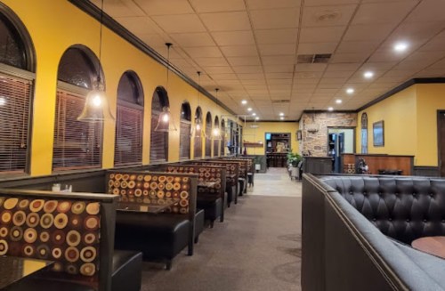 Interior of a restaurant featuring yellow walls, booth seating, and warm lighting, creating a cozy atmosphere.