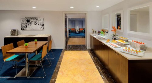 Modern kitchen area with a dining table, snacks on a counter, and a stylish, bright interior design.