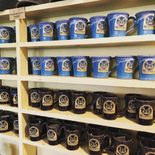 A display of blue and dark mugs with logos, arranged neatly on shelves.