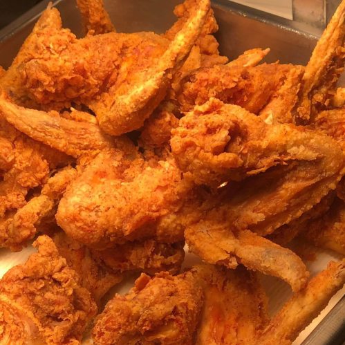 A close-up of crispy, golden-brown fried chicken wings piled in a tray.