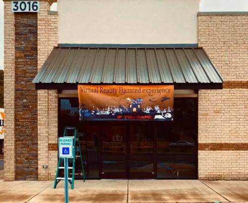 A storefront with a sign reading "Virtual Reality Haunted Experience" and a ladder nearby.