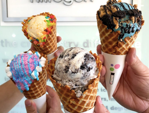Four colorful ice cream cones held by hands, featuring various flavors and toppings against a light background.