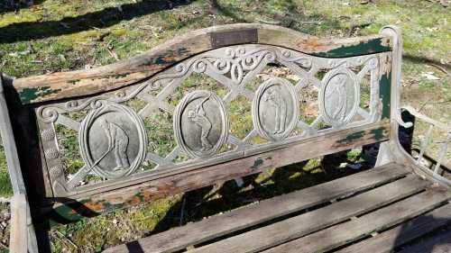 A weathered wooden bench with decorative carvings depicting various figures in circular frames.