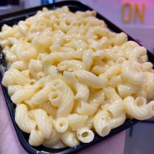 A close-up of a black container filled with creamy macaroni pasta.