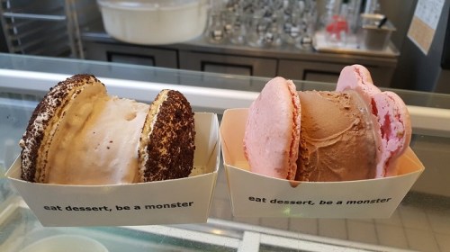 Two ice cream sandwiches in paper containers, one with chocolate and the other with strawberry, both labeled "eat dessert, be a monster."