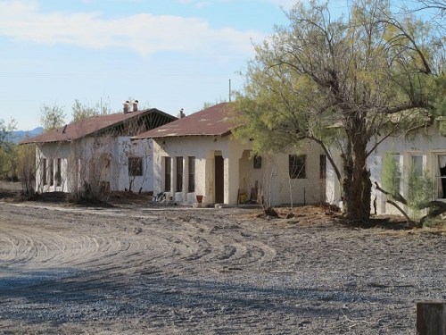 Abandoned building with a weathered exterior, surrounded by sparse vegetation and a gravel path.
