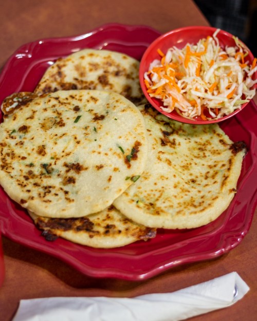 Three golden-brown tortillas served on a red plate, accompanied by a small bowl of coleslaw.