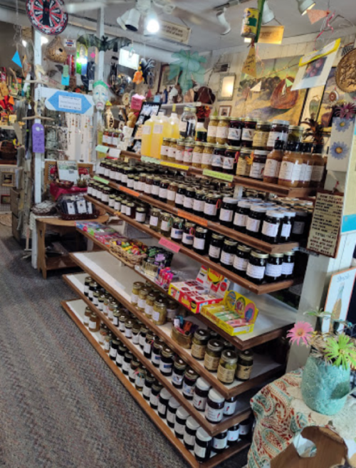 A display of jars and bottles on wooden shelves in a colorful shop filled with various crafts and decorations.