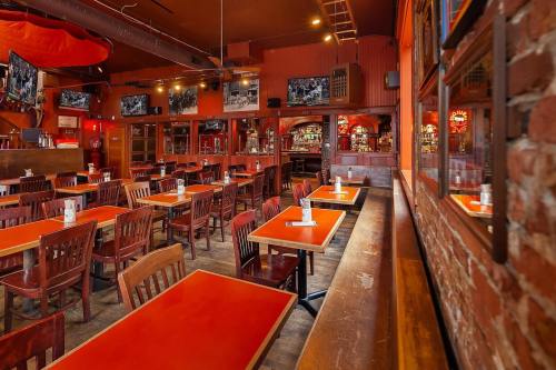 Interior of a restaurant with wooden tables and chairs, brick walls, and multiple TVs on the walls.