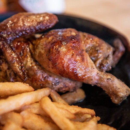 A close-up of a plate featuring grilled chicken and crispy French fries.