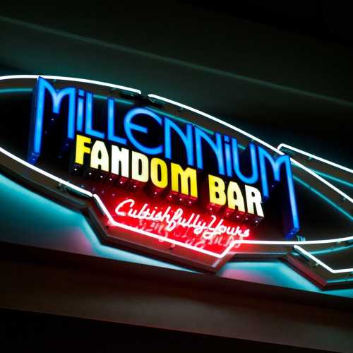 Neon sign for "Millennium Fandom Bar" with colorful lights and a retro design.