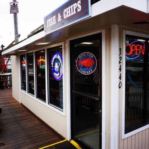 Exterior of a fish and chips restaurant with a sign reading "Fish & Chips" and an "Open" neon sign.