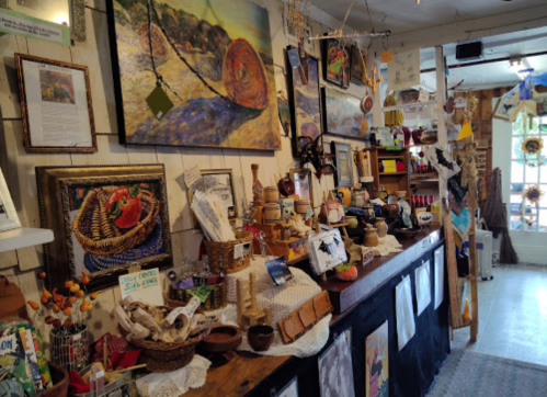 A cozy shop interior filled with colorful artwork, handmade crafts, and decorative items on display.