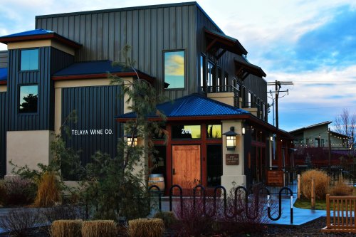 Exterior of Telaya Wine Co. building with modern architecture, surrounded by landscaping and a cloudy sky.
