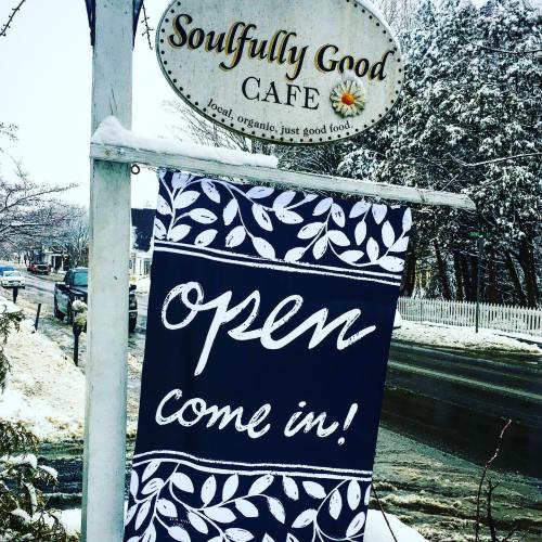 A sign outside "Soulfully Good Cafe" reads "Open, come in!" with a snowy street in the background.