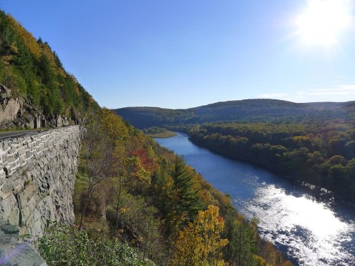 Scenic view of a river winding through autumn-colored hills under a clear blue sky.