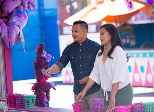 A man and woman play a carnival game, reaching for colorful baskets at a festive outdoor fair.