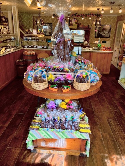 A colorful display of Easter chocolates and treats in a shop, featuring baskets and a large chocolate centerpiece.