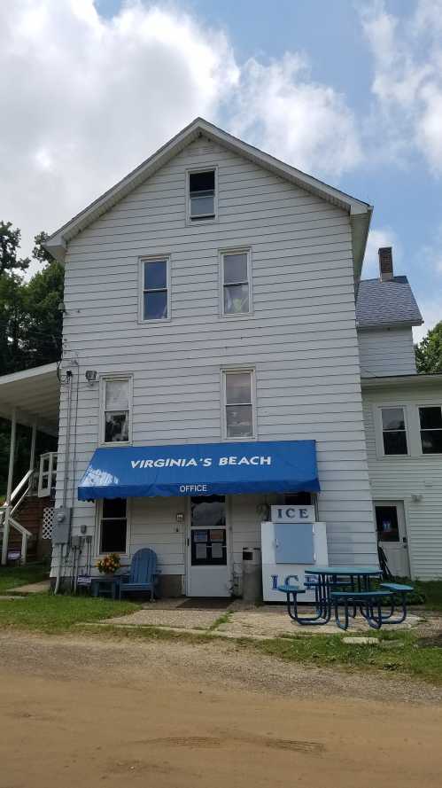 A three-story building with a blue awning labeled "Virginia's Beach Office" and an ice vending machine outside.