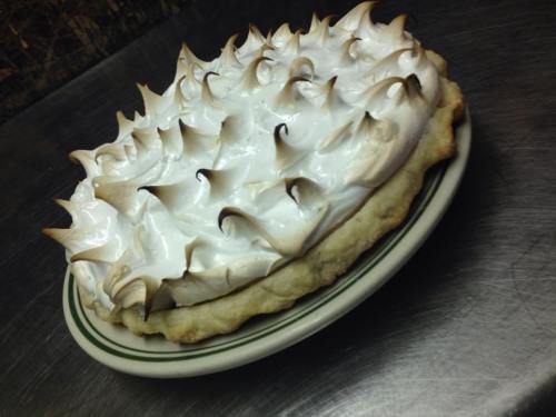 A beautifully baked pie with a golden-brown meringue topping, resting on a white plate.