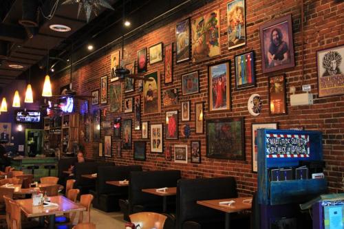 A cozy restaurant interior with brick walls adorned with colorful framed artwork and wooden tables.
