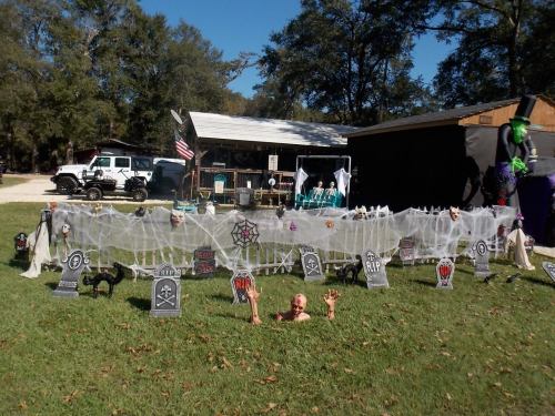 A Halloween-themed yard display with tombstones, spider webs, and spooky decorations in front of a house.