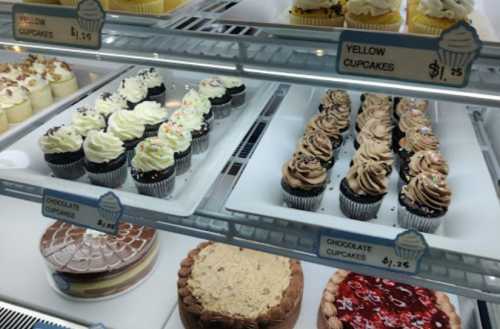 Display case filled with various cupcakes and cakes, including chocolate and yellow cupcakes, all priced at $1.25.