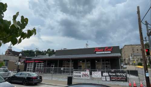 A new restaurant building with a "Coming Soon" sign, surrounded by construction barriers and cloudy skies.