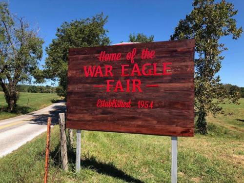 Sign for the War Eagle Fair, established in 1954, set against a clear blue sky and green fields.