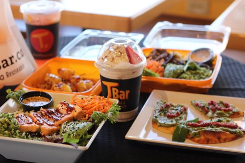 A variety of colorful dishes including salads, grilled chicken, and a dessert drink, arranged on a table.
