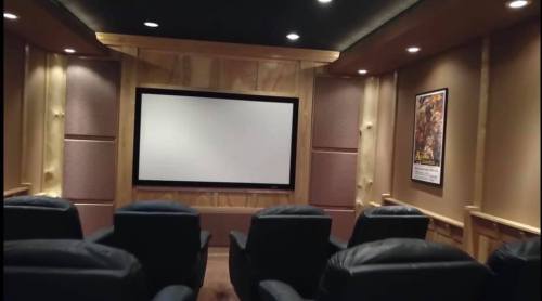Home theater room with leather seating, a large screen, and wooden paneling, creating a cozy viewing atmosphere.