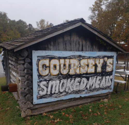 A rustic wooden building with a sign that reads "Coursey's Smoked Meats" in bold letters.