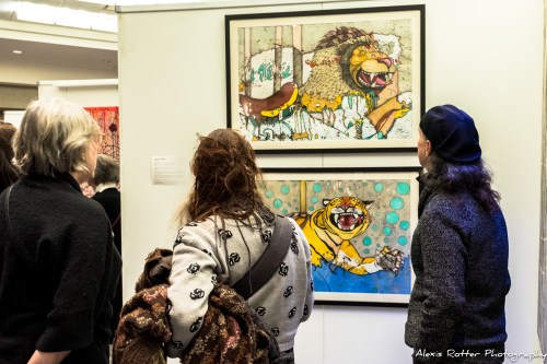 Visitors admire colorful artwork featuring animal characters at an art exhibition.