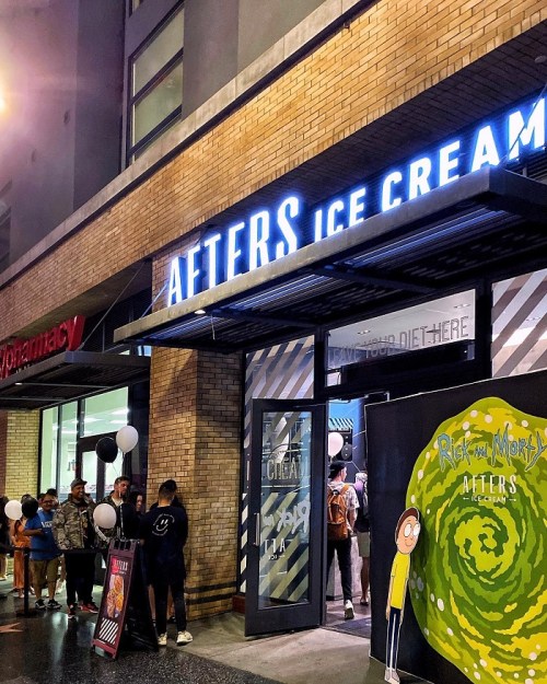 A storefront for Afters Ice Cream featuring a "Rick and Morty" themed display and a line of customers outside.
