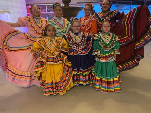 A group of girls in colorful traditional dresses pose together, showcasing vibrant patterns and cultural attire.